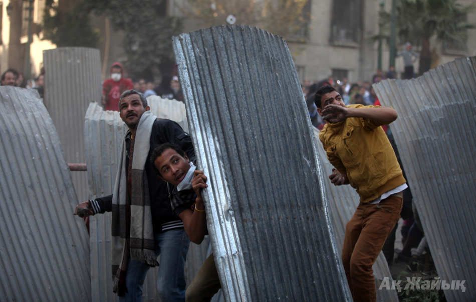 Egyptian protesters take cover as they clash with riot police, not seen, near Tahrir Square, Cairo, Egypt, Friday, Jan. 25, 2013. Two years after Egypt’s revolution began, the country’s schism was on display Friday as the mainly liberal and secular opposition held rallies saying the goals of the pro-democracy uprising have not been met and denouncing Islamist President Mohammed Morsi. With the anniversary, Egypt is definitively in the new phase of its upheaval. (AP Photo/Khalil Hamra)