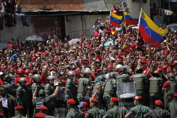 Supporters of late Venezuelan President Hugo Chavez crowd a street in Caracas to watch his coffin pass by as it is taken from the hospital where he died Tuesday. The coffin will be placed at a military academy where it will remain until his funeral. (Rodrigo Abd / Associated Press / March 6, 2013)