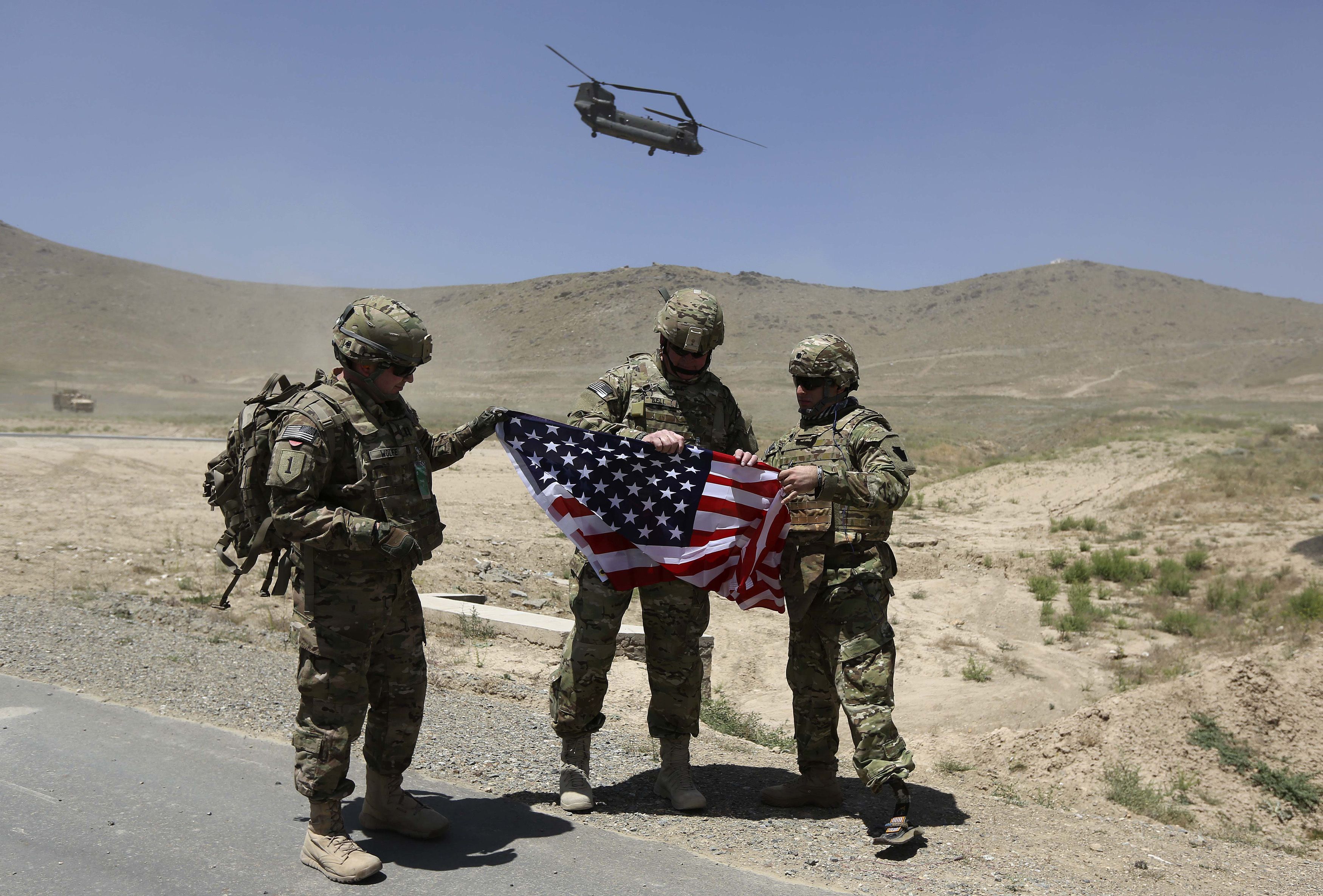 NATO soldiers stand with U.S. flag as a Chinook helicopter takes off after a security handover ceremony at a military academy outside Kabul. ©REUTERS/Omar Sobhani  For more information see: http://en.tengrinews.kz/opinion/384/ Use of the Tengrinews English materials must be accompanied by a hyperlink to en.Tengrinews.kz