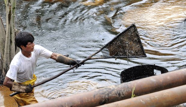 An employee of state-owned Petroecuador works on a cleaning operation of a 30-year old oil spill at the Rumipamba commune, 200 mt form the Auca Sur 1 oil well --operated by Chevron Texaco in the seventies-- in the province of Orellana, Amazonia, on Feb. 20, 2011. Photograph by Rodrigo Buendia/AFP via Getty Images