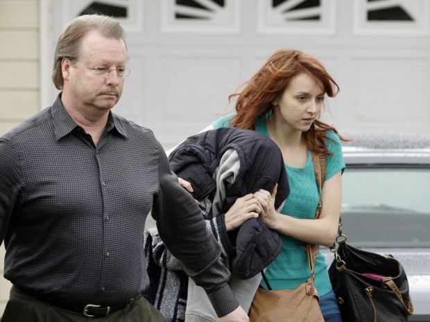 A woman believed to be Amanda Knox, centre, is hidden under a jacket while being escorted from her mother's home to a car by family members , Thursday, Jan. 30, 2014, in Seattle.