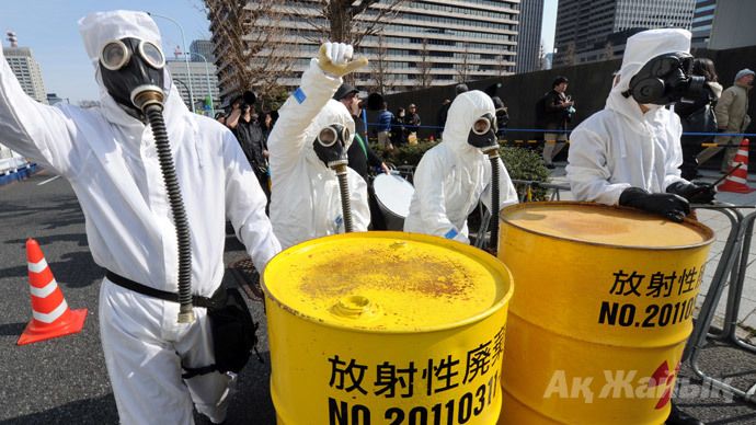 People wearing protective suits and masks shout slogans next to mock drums of nuclear waste from the Fukushima Daiichi nuclear power plant, during a march denouncing nuclear power plants in Tokyo on March 9, 2014. (AFP Photo