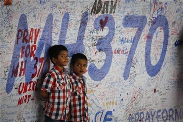wo Malaysian children stand in front of a message board offering prayers to those aboard the missing plane. (Associated Press)