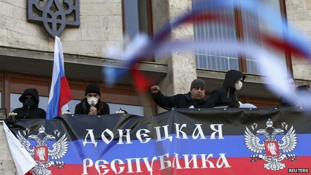 Pro-Russia protesters hang a banner as they storm the regional government building in Donetsk April 6, 2014 A breakaway group broke into the regional administration building and hung a banner