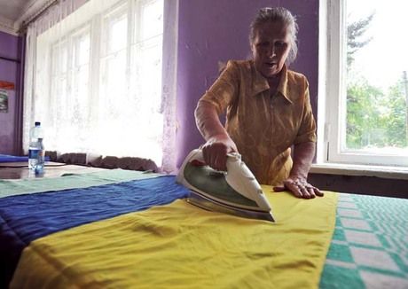 A member of an election commission irons a Ukrainian flag at a polling station ahead of the presidential election at Octyabr village in Donetsk Oblast. Ukrainians will choose a president on May 25.