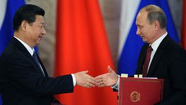 Russia's President Vladimir Putin (R) shakes hands with his Chinese counterpart Xi Jinping