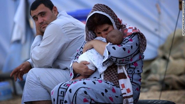 A woman cradles her baby Thursday, June 12, at a temporary camp set up in Aski Kalak, Iraq, to shelter those fleeing the violence in northern Nineveh province.
