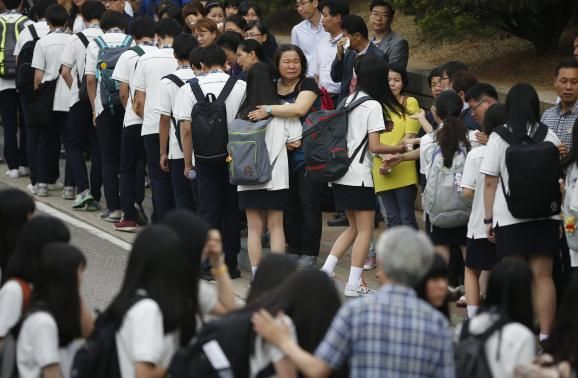 Relatives of the April 16 ferry disaster victims comfort students who survived the accident as they make their way back to school in Ansan June 25, 2014. 