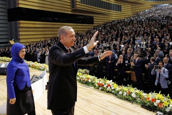 Prime Minister Recep Tayyip Erdogan, center, with his wife, Emine, announces his presidential bid before party members in Ankara on Tuesday. (AFP)