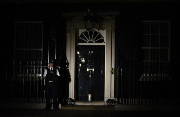 A policeman stands guard as a lantern is placed at the front door of Number 10 Downing Street during 