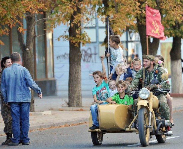Children ride the motorcycle of an armed pro-Russian militant in the eastern Ukrainian city of Lugansk on September 14, 2014 during the celebration of the day of the city.