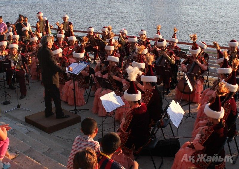 Dina Nurpeissova folk orchestra performing on the bank of the Ural River on July 6, 2014.