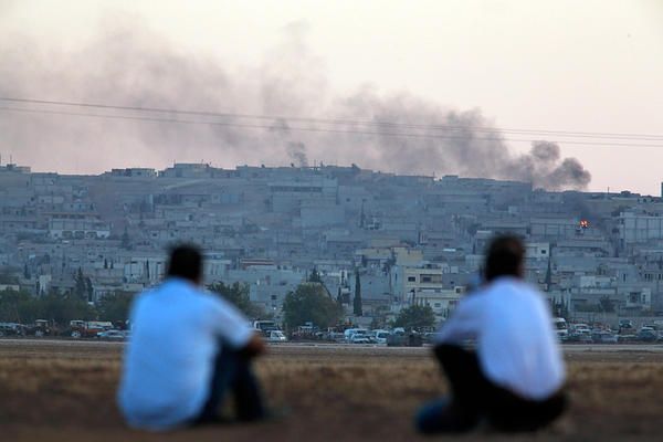 Turkish Kurds sit on the outskirts of Suruc, on the Turkey-Syria border, as they watch smoke rising from a fire following an airstrike in Kobane, Syria, where the fighting between militants of the Islamic State group and Kurdish forces intensified, Tuesday, Oct. 7, 2014. 