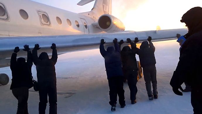 Passengers pushing the plane with its wheels frozen (Screenshot from youtube.com)