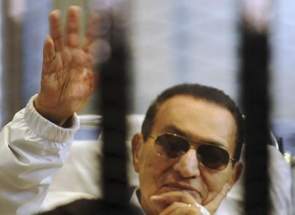 Former Egyptian President Hosni Mubarak waves to his supporters inside a cage in a courtroom at the police academy in Cairo April 13, 2013.