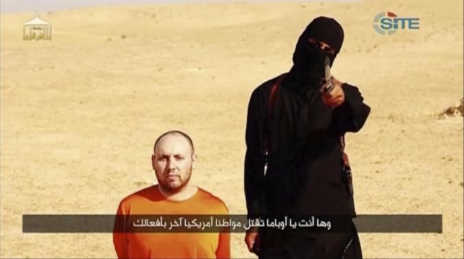 A masked, black-clad militant, who has been identified by the Washington Post newspaper as a Briton named Mohammed Emwazi, stands next to a man purported to be Steven Sotloff in this still image from video.