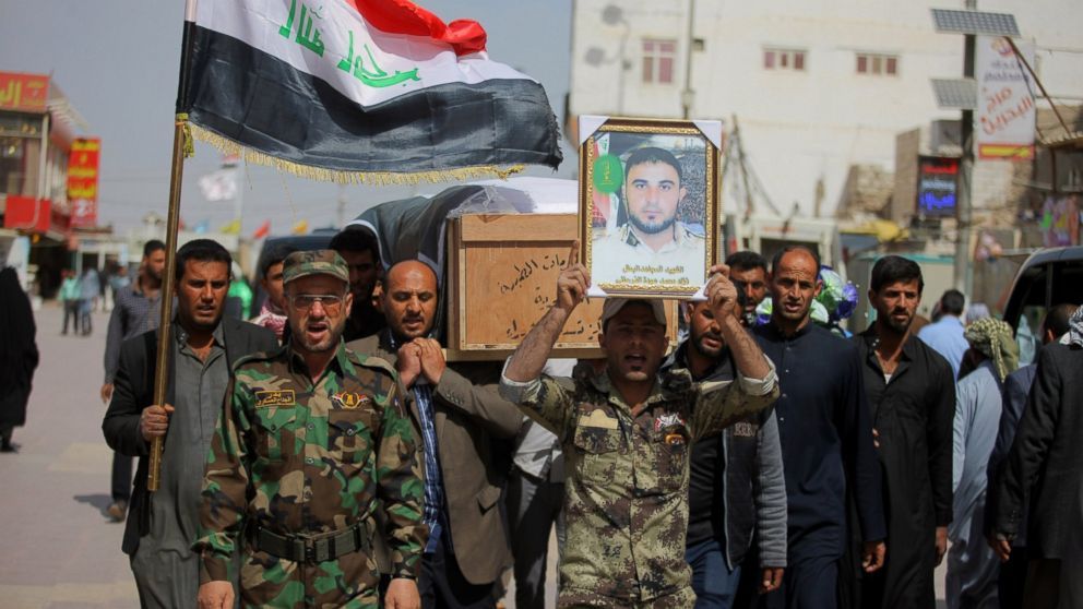 Members of the Iraqi Shiite militant group Badr Brigades carry the coffin of Mohammed Fuad and a poster with his picture during his funeral procession in Najaf, Iraq, Monday, March 9, 2015. Iraqi security forces on Tuesday retook a town next to the militant-held city of Tikrit as they pressed their offensive against Islamic State militants.